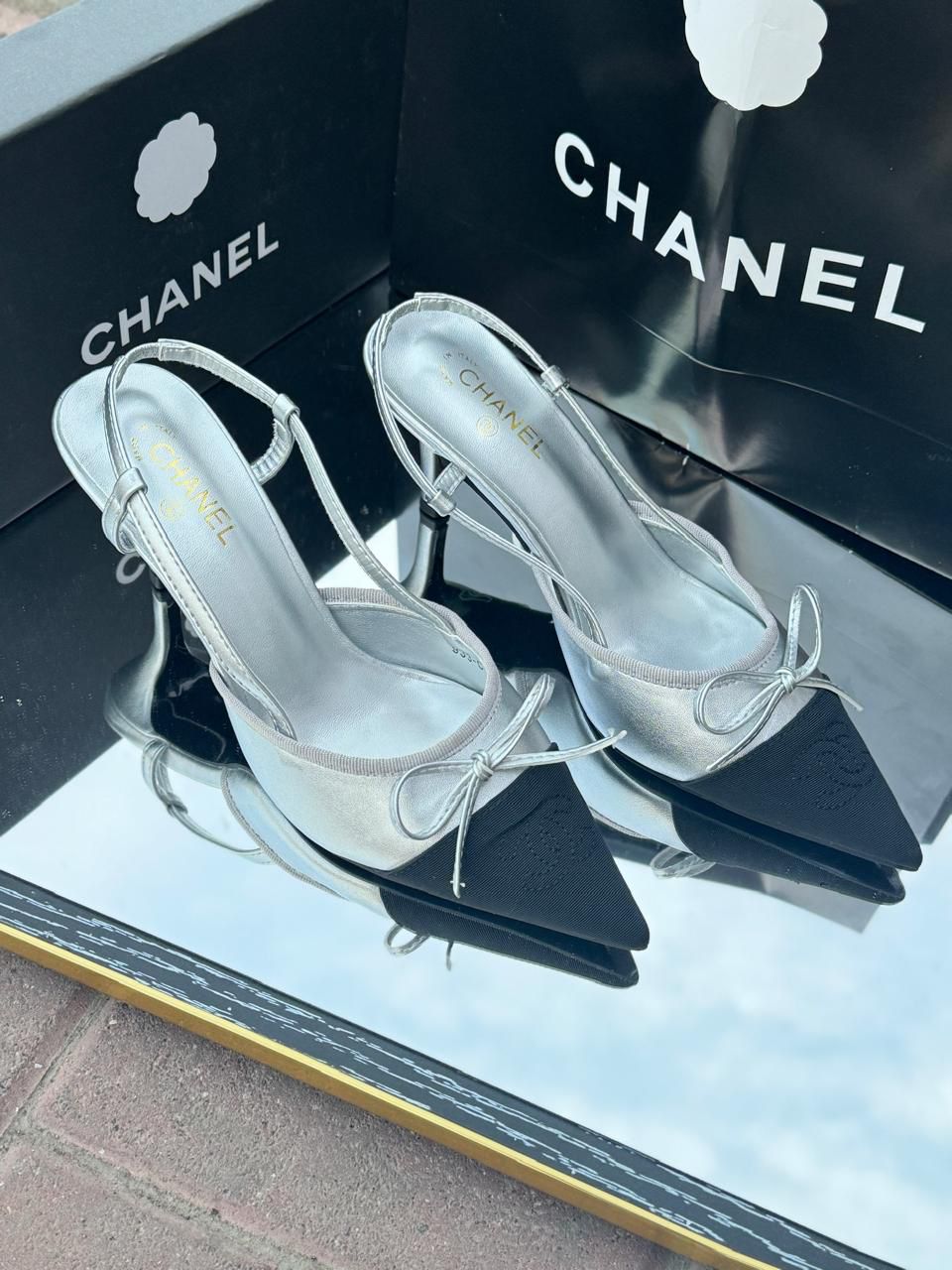 Chanel Metallic Silver Slingback Heels with Black Cap Toe & Bow – Modern Designer Elegance